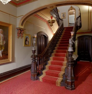 Staircase with restored red carpet with leafy patterns and brown and gold border