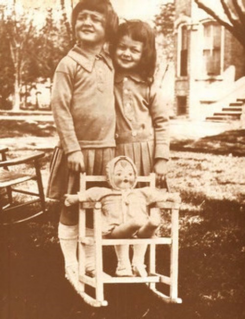 Sheila and Philippa on the lawn of Glanmore with a doll in a small rocking chair