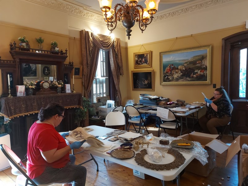 Two museum staff processing a large collections of original artifacts recently donated to the museum