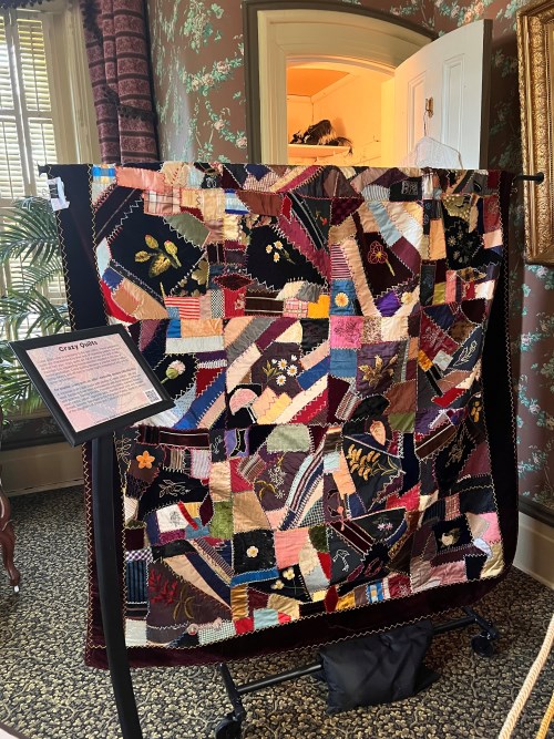 A Victorian crazy quilt displayed hanging on rack in main bedroom